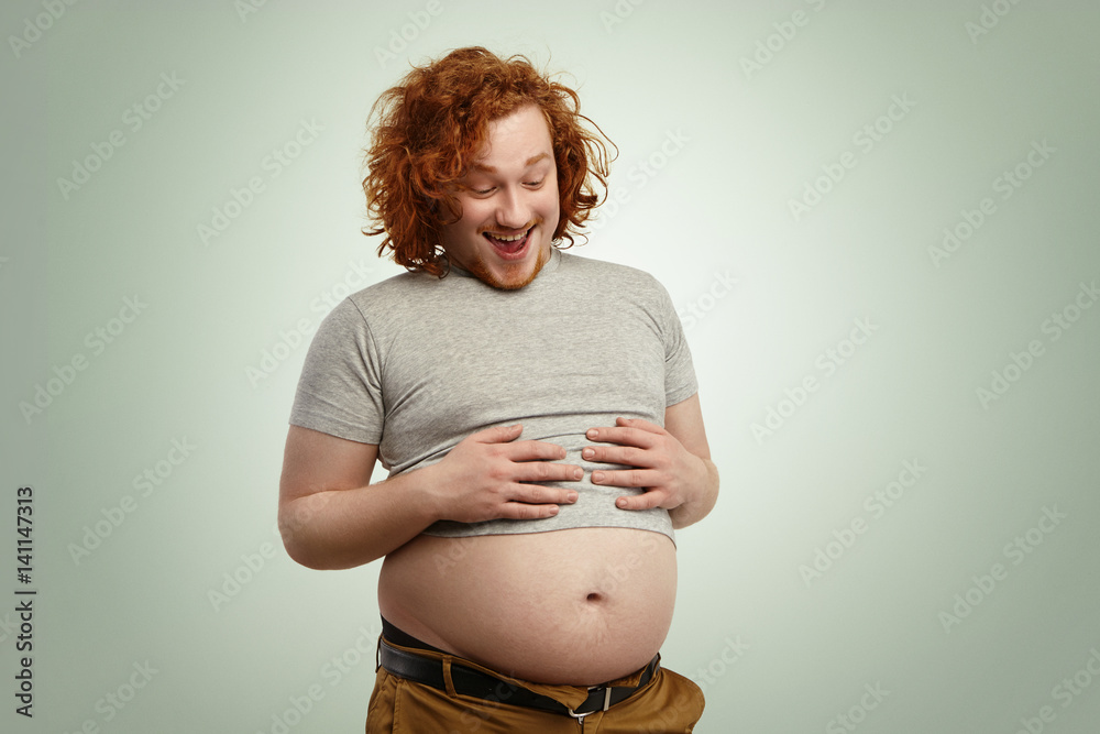 Indoor shot of funny overweight young Caucasian male wearing