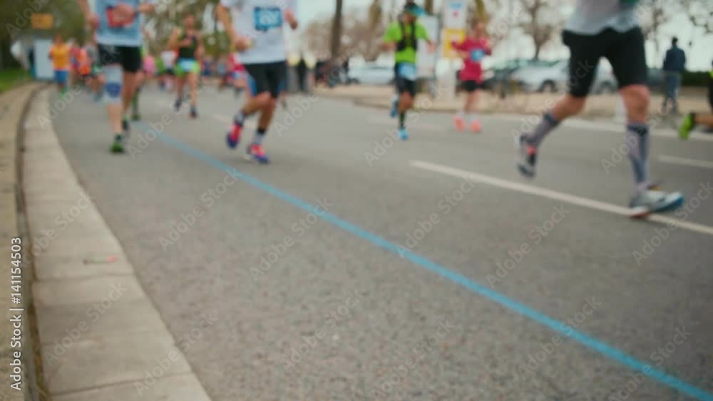 A blurred shot of the marathon runners running in the background through the palm tree alley on the beach of barcelona A blurred shot of the marathon runners running in the background through the palm tree alley on the beach of barcelona