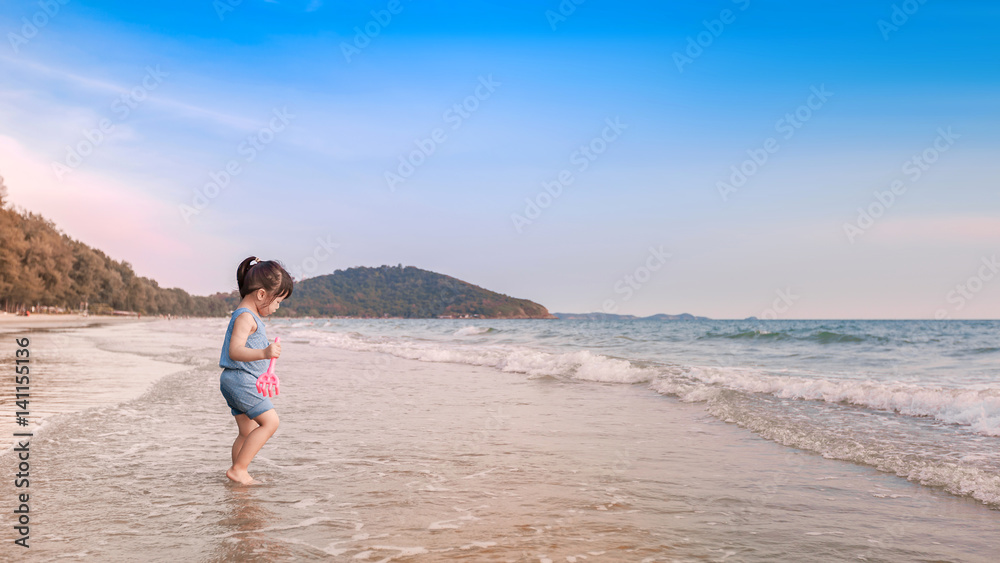 little girl playing on the beach in sunset