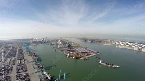 Aerial flight over harbor area industrial landscape on left side container terminal ocean containers and cranes for loading and unloading freight ships on right side oil storage containers 4k photo