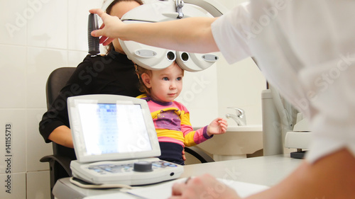 Optometrist in clinic checking little girl's vision - children's ophthalmology