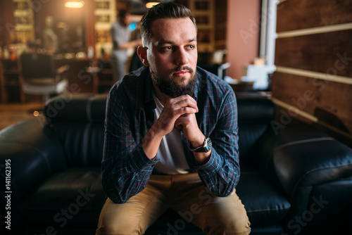 Bearded man sitting on a couch at the barbershop