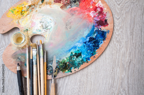 Materials for creativity, palette and brush for painting on a wooden background. The concept of fine art.