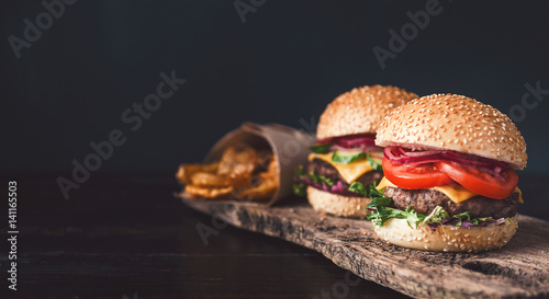 Obraz na płótnie two mouth-watering, delicious homemade burger used to chop beef. on the wooden table. w salonie