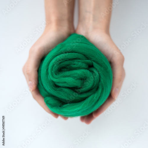 Close-up of green merino wool ball in hands.
