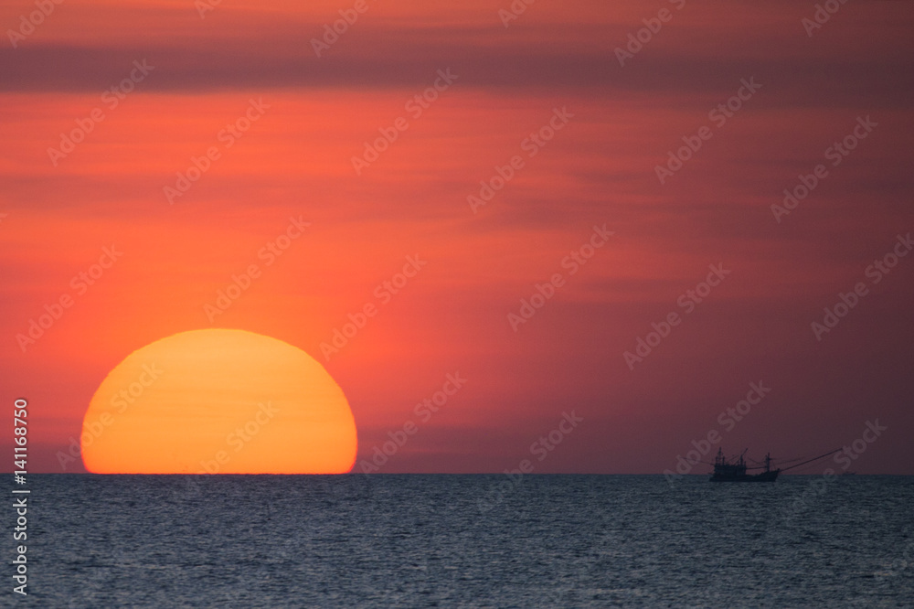 Big sun and a fisherman boat at sunset in Phuket - Thailand