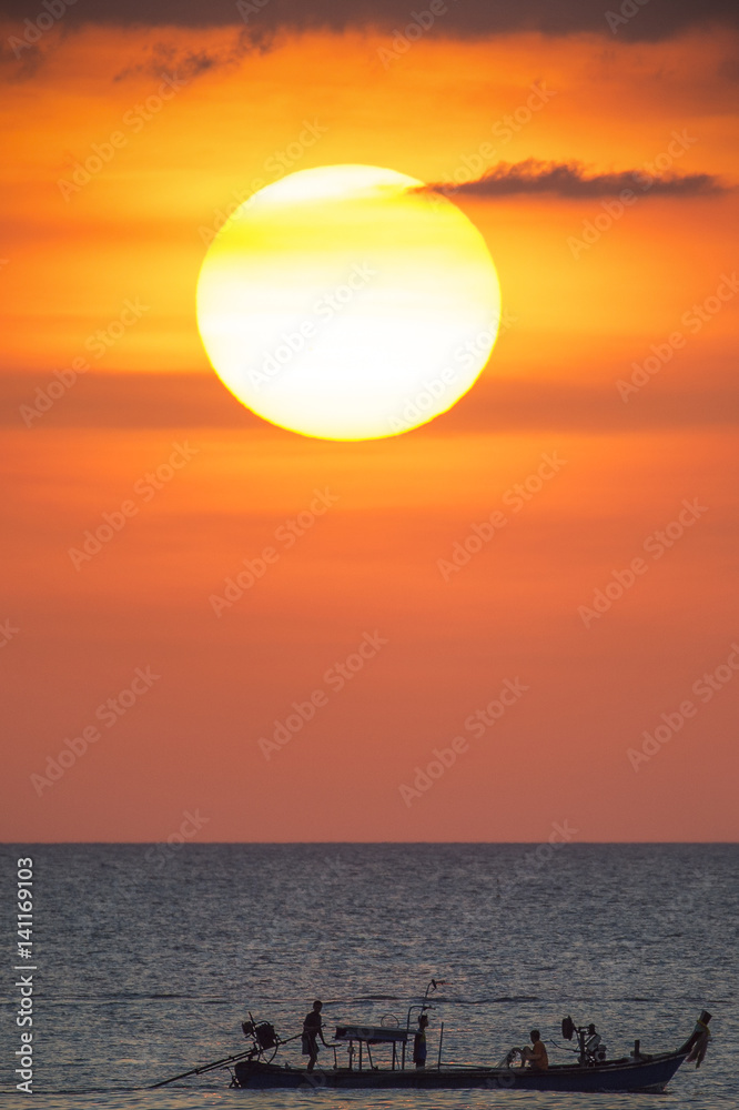 Big sun and a fisherman boat at sunset in Phuket - Thailand