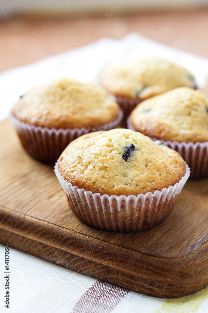 Homemade muffins with blueberries on a wooden board