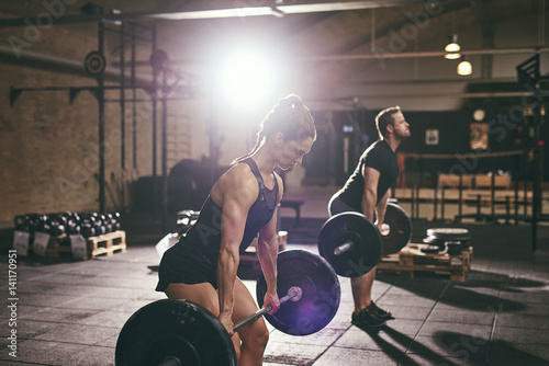 Fit muscular people lifting barbells in gym