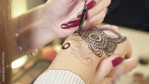 Woman making a flower mehendi with black henna
