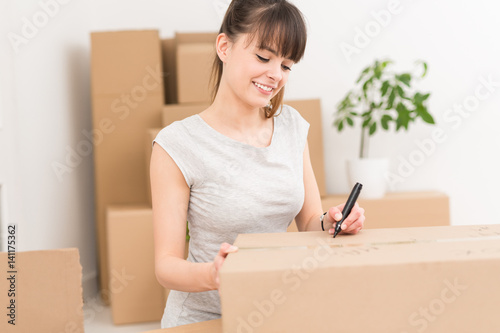 Young woman signs a box while moving. © REDPIXEL