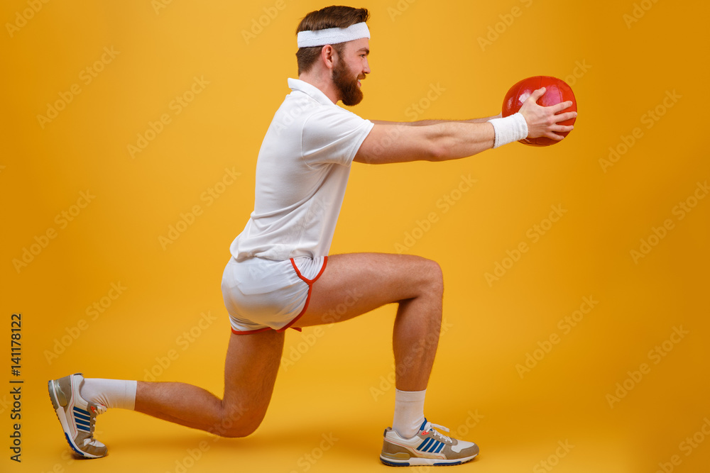 Concentrated young sportsman make sport exercises holding ball.