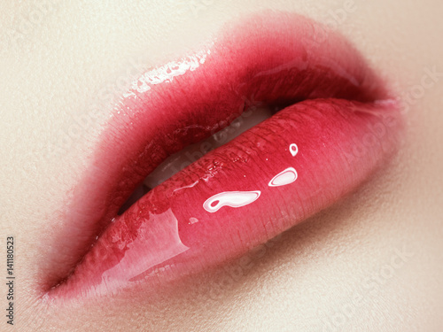 Close-up beautiful female lips with bright lipgloss makeup. Perfect clean skin, light fresh lip make-up. Beautiful spa macro shot with tender pink lip gloss. Spa and cosmetics photo