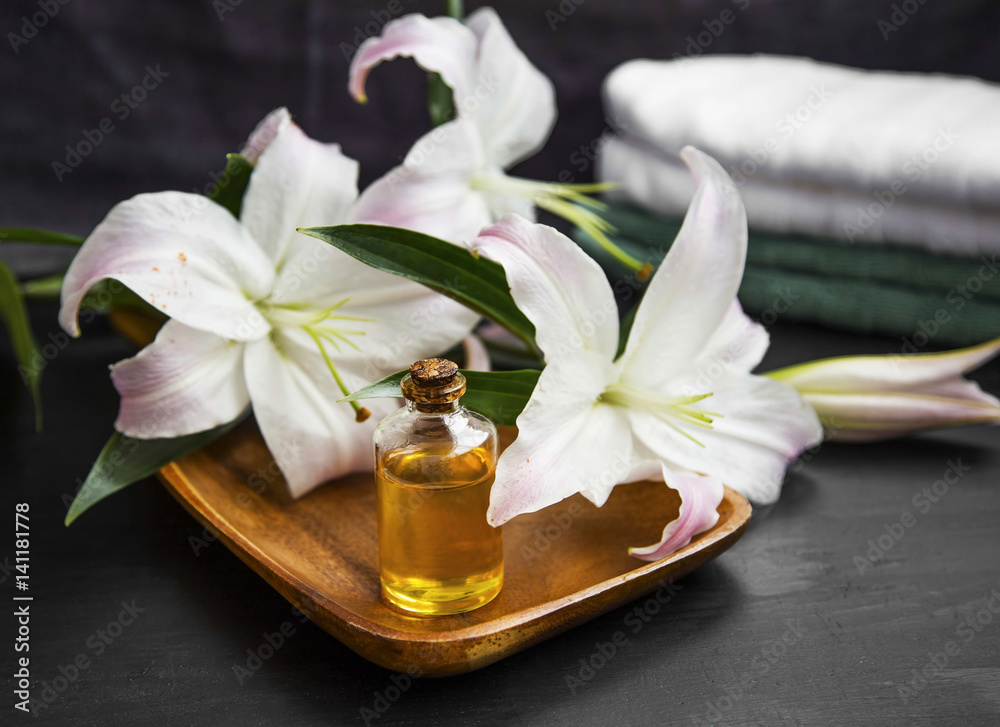 Spa aromatherapy setting, bath oil with lily flowers and towels Spa aromatherapy setting, bath oil with lily flowers and towels