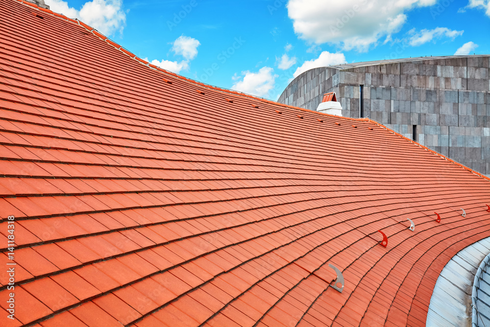 Naklejka premium Tile roof with blue sky and clouds in background
