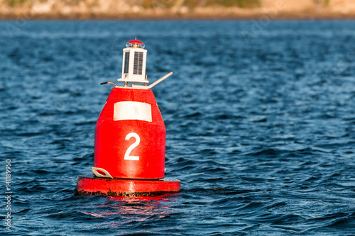 Фотография Red (Nun) companion buoy and boating channel marker in harbor.
