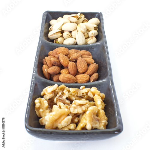 Assorted mixed nuts in black plate on white background
