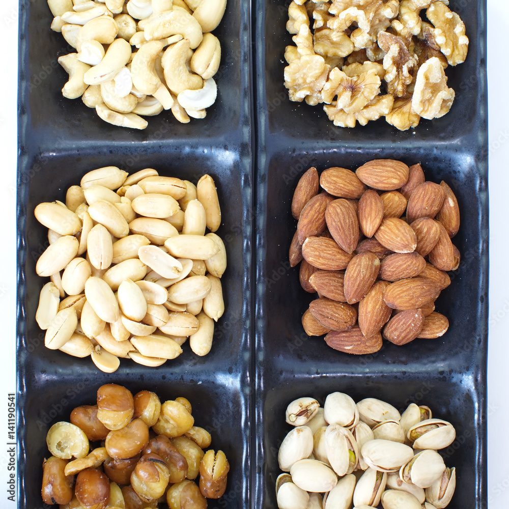 Assorted mixed nuts in black plate on white background