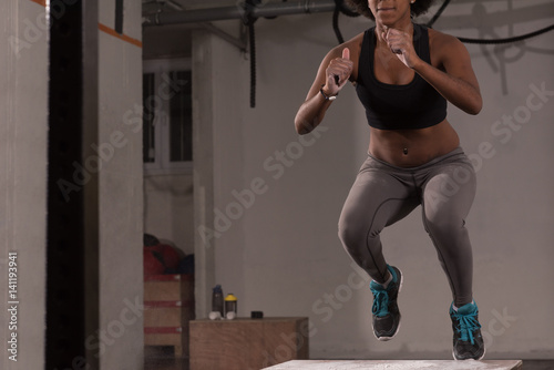 black woman is performing box jumps at gym