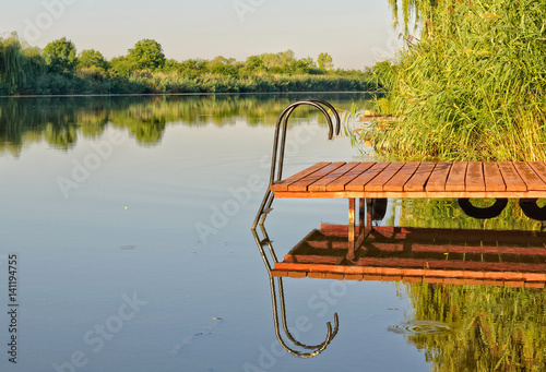 Φωτογραφία Pier and its image in the scenic Holt-Koros River at Bekesszentandras, Hungary