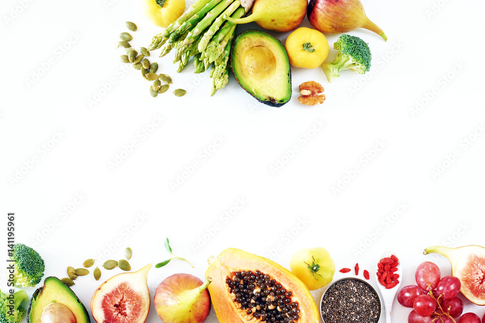 Naklejka premium Fresh veggies and fruits frame on white background with copy space. Detox or clean-eating concept with avocado, papaya, grape, broccoli, figs, nuts, seeds, superfoods. 
