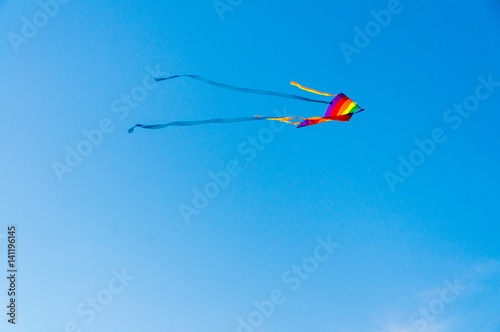 Beutiful colorful kite flying in the wind with blue sky in background.