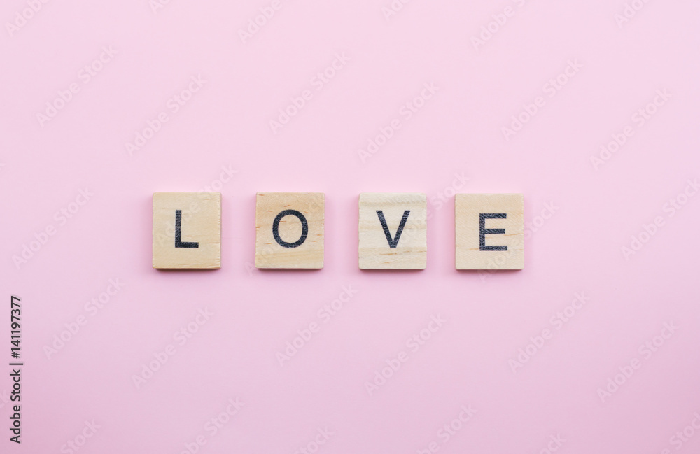 Text wooden blocks spelling the word love on pink background Text wooden blocks spelling the word love on pink background