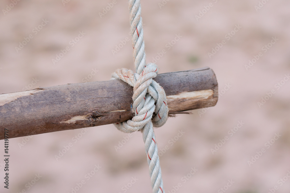 A rope is tied in a knot around a fence post , rope tied knot wood pole