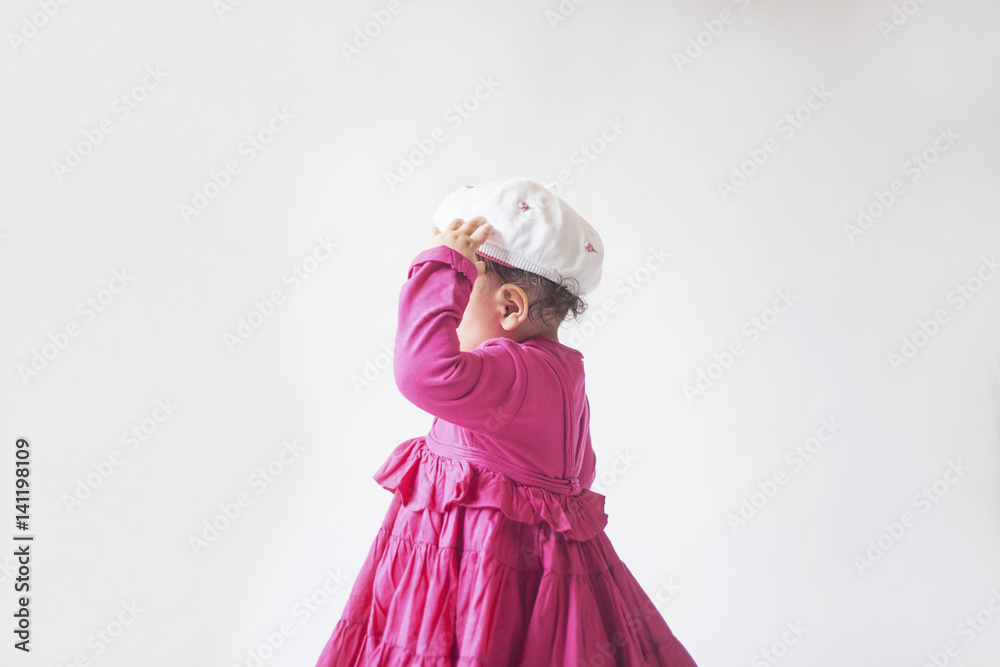 child walking in a pink dress with hat on