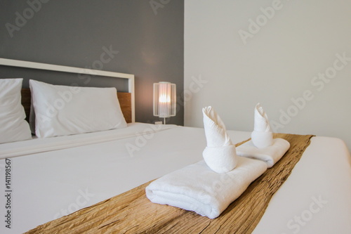 Two towels on the bed in hotel room.
