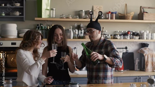 man is opening bottle of champagne on a home kitchen party photo