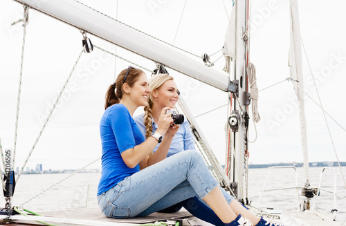 Two beautiful, attractive young girls taking pictures on a yacht. Traveling, vacation, tourism, concept.