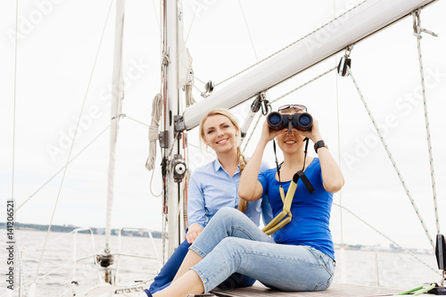 Two beautiful, attractive young girls with binocular on a yacht. Traveling, vacation, tourism, concept. © Acronym