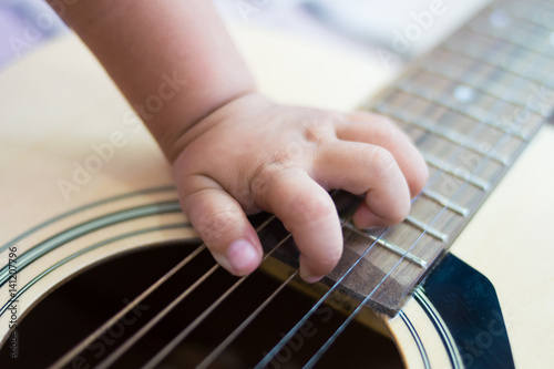close up hand baby playing the guitar