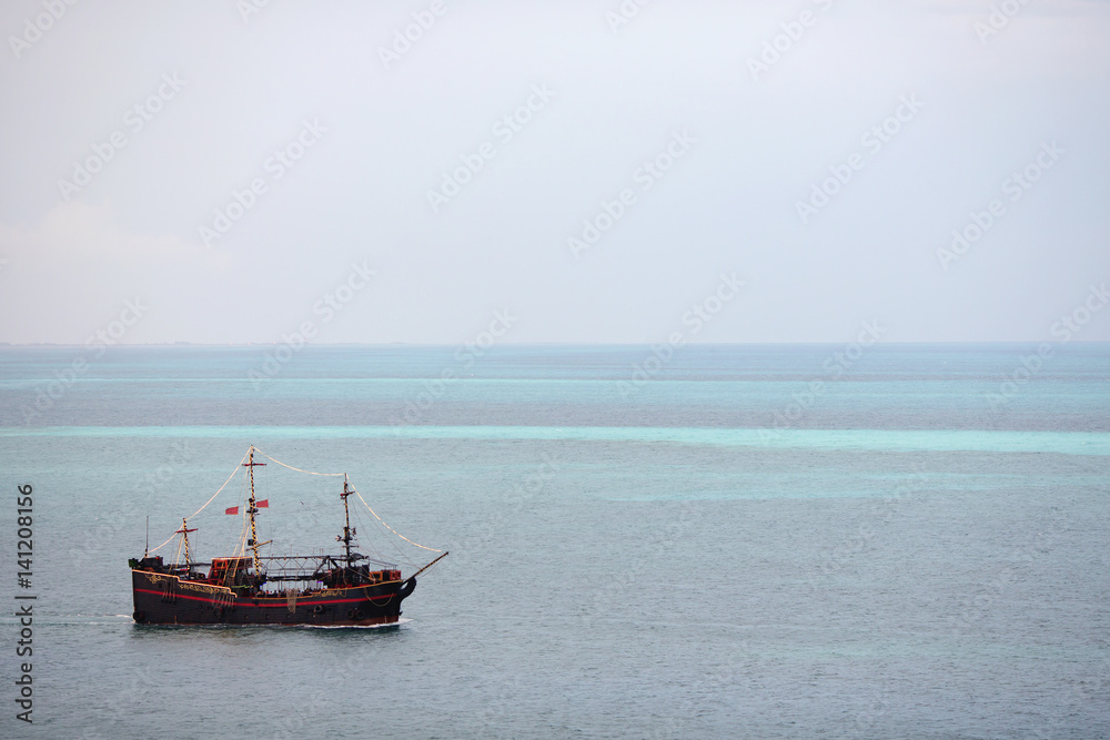 Pirate ship in the middle of the Caribbean ocean. Wallpaper. Boat composed to the left. Copy space. Pirate ship in the middle of the Caribbean ocean. Wallpaper. Boat composed to the left. Copy space.
