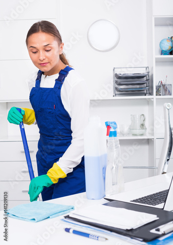 Fototapeta Naklejka Na Ścianę i Meble -  Young female cleaner polishing surfaces at office