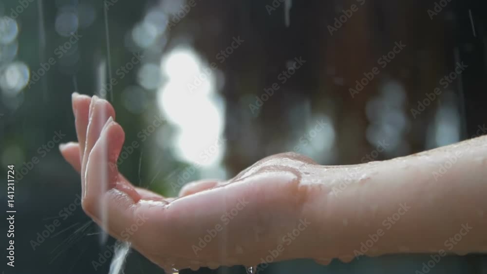 Women's hand covered in droplets of heavy rain in close-up