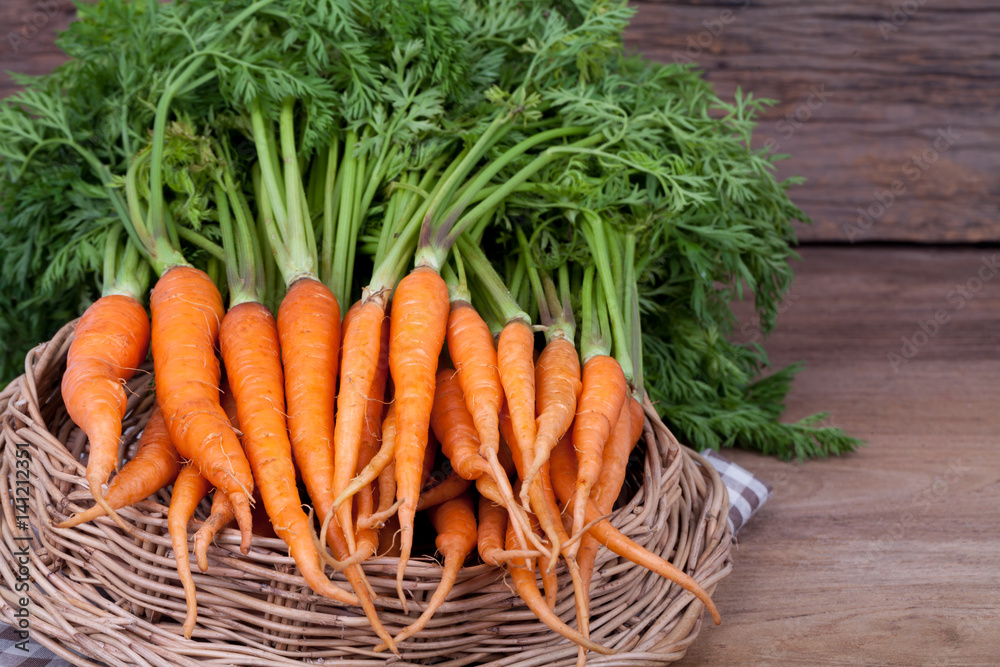 Bunch of fresh carrots with green leaves over wooden background Bunch of fresh carrots with green leaves over wooden background