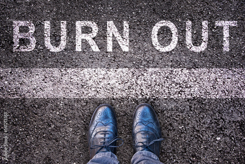 Tableau sur toile Word burn out written on asphalt with legs and shoes, burn out concept