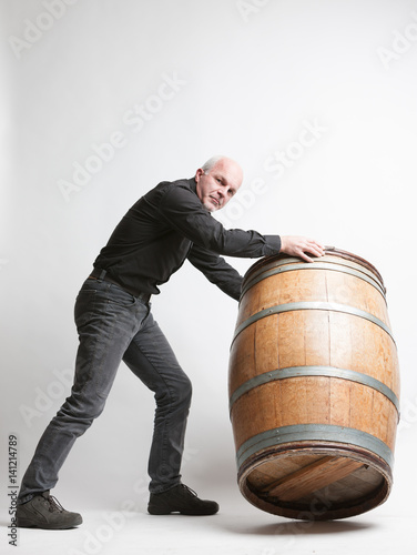 Man moving a large oak wine or beer barrel photo