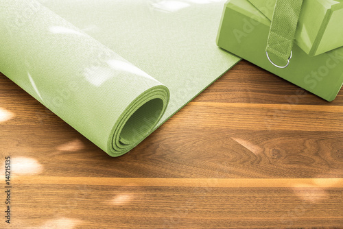 Yoga mat on wooden floor in evening light with shadows from window