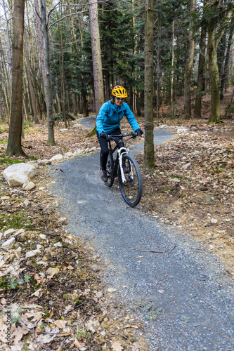 Mountain biking women riding on bike in early spring mountains forest landscape. Woman cycling MTB enduro flow trail track. Outdoor sport activity.