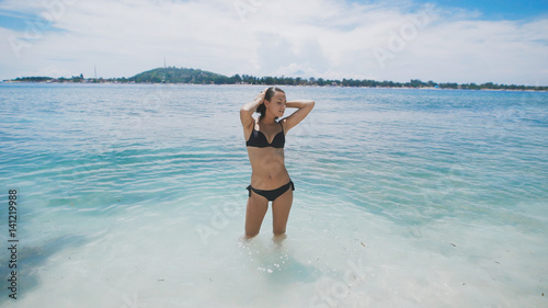 A tourist beach in a bathing suit. She enjoys pure and endless turquoise ocean on the island of Bali. She is accompanied by great weather, gorgeous views and a positive mood. © kustvideo