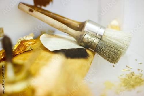 Artisan tools with a golden paper and brushes in workshop