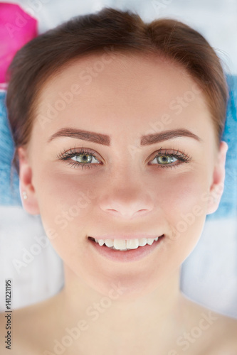Closeup of an attractive young smiling woman receiving massage.
