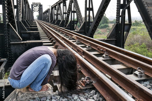 Foto Desperate woman alone beside railway in foetal position, depression, sadness, su