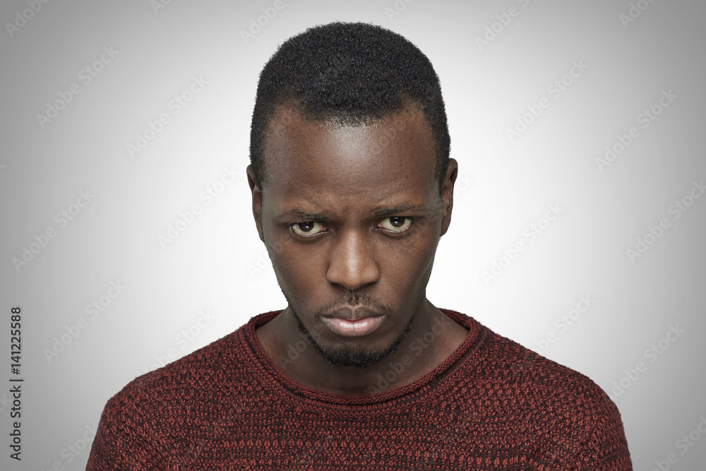 Close up portrait of displeased, upset and pissed off young African American male. Black man looking and frowning at camera, having bad mood, feeling dissatisfied. Negative human face expressions Close up portrait of displeased, upset and pissed off young African American male. Black man looking and frowning at camera, having bad mood, feeling dissatisfied. Negative human face expressions
