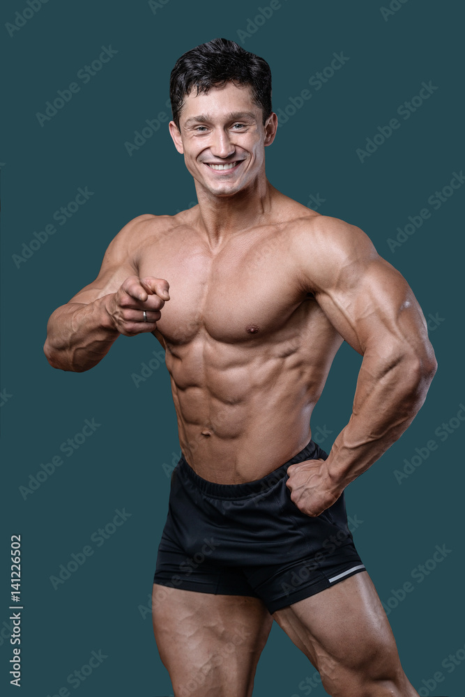 Handsome caucasian muscular man on diet point fingers in gym..