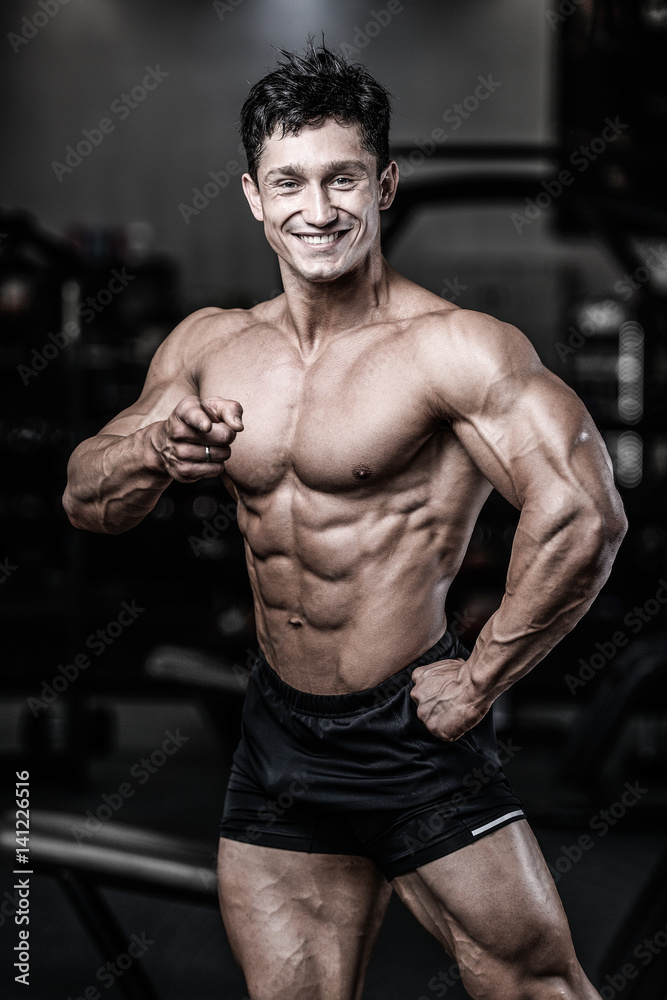 Handsome caucasian muscular man on diet point fingers in gym.. Handsome caucasian muscular man on diet point fingers in gym..
