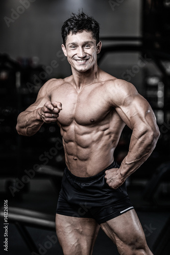 Handsome caucasian muscular man on diet point fingers in gym..
